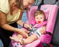 Woman fastening her son on a baby seat