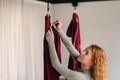 A woman fastens a hook from a hanging hammock for yoga in the gym