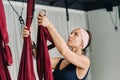 A woman fastens a hook from a hanging hammock for yoga in the gym