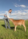 Woman feeding baby calf in field Royalty Free Stock Photo