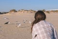 Woman is feeding birds gulls and crows on a sandy beach. Royalty Free Stock Photo