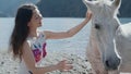 Pregnant woman petting white horse by the mountain lake at beautiful sunlight. beauty and nature concept. Lifestyle and