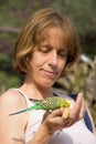 Woman feeding green budgerigar on hand Royalty Free Stock Photo