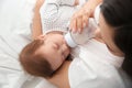 Woman feeding her baby from bottle on bed Royalty Free Stock Photo