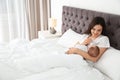 Woman feeding her baby from bottle on bed. Royalty Free Stock Photo