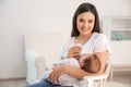 Woman feeding her baby from bottle in nursery at home. Royalty Free Stock Photo
