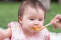 woman feeding her beautiful little daughter - mother hand and close up portrait of adorable and happy baby girl eating baby Royalty Free Stock Photo