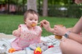 woman feeding her beautiful little daughter - mother hand and close up portrait of adorable and happy baby girl eating baby Royalty Free Stock Photo