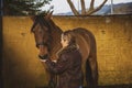 Woman feeding her brown horse with her hand in the stable Royalty Free Stock Photo