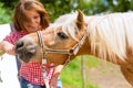 Woman feeding horse on pony farm Royalty Free Stock Photo