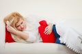 Woman feeling stomach cramps lying on cofa Royalty Free Stock Photo