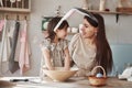 Woman feels like child again. Mother and daughter in bunny ears at easter time have some fun in the kitchen at daytime