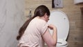 Woman feels nauseous sitting near toilet in bathroom