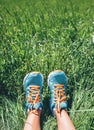 Woman feet in bright blue running shoes are in high green grass