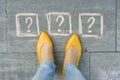 Woman feet with 3 question marks in front of her legs painted on the grey sidewalk Royalty Free Stock Photo