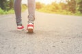 Woman feet with red sneaker shoes walking on the roadside.