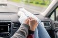 Woman feet in socks on car dashboard. Man driver holds the hand of a female passenger traveling on the highway. Couple on a trip.