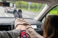 Woman feet in socks wrapped in a plaid on car dashboard. Man driver holds the hand of a female passenger traveling on the highway.