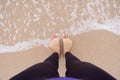 Woman feet standing on the beach and touching water