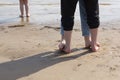 Woman feet standing on man feet and child feet on the sand beach barefoot