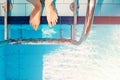 Woman feet standing near the stairs in swimming pool with blue water, Royalty Free Stock Photo