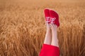 Woman feet up in red shoes funny sticking out of on wheat field background