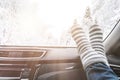 Woman feet in warm woolen socks on car dashboard over snow view Royalty Free Stock Photo