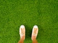 Woman feet wear vintage soft brown sneaker shoes stand on green grass floor Royalty Free Stock Photo