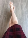 Woman feet wearing pink sandals and scot dress of fashion. Selfie of feet and legs in pink shoes on wooden background