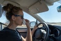 Woman female driver uses a tissue to blow her nose while driving. Concept for distracted driving, multi tasking, health issues,