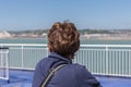 Woman at ferry leaving Dover looking backwards to English coast