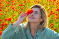 Woman in a field of red poppies enjoys nature. A young woman in a poppy field. Spring girl.