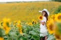 Woman in the field of sunflowers. A happy, beautiful young girl in a white hat is standing in a large field of sunflowers. Summer Royalty Free Stock Photo