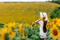Woman in the field of sunflowers. A happy, beautiful young girl in a white hat is standing in a large field of sunflowers. Summer Royalty Free Stock Photo