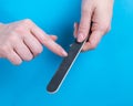 Woman filing her nails on a blue background. Royalty Free Stock Photo