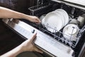 Woman fill the used dish in dishwasher machine in kitchen at home.Hand of female holding the shelf.