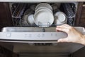 Woman fill the used dish in dishwasher machine in kitchen at home.Hand of female holding the shelf