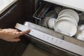 Woman fill the used dish in dishwasher machine in kitchen at home.Hand of female pushes starts button