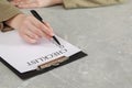 Woman filling Checklist at grey marble table, closeup. Space for text