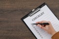 Woman filling Checklist at wooden table, top view. Space for text Royalty Free Stock Photo