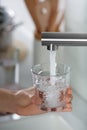 Woman filling glass with tap water from faucet in kitchen, closeup Royalty Free Stock Photo