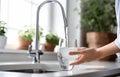 Woman filling glass with tap water from faucet in kitchen Royalty Free Stock Photo