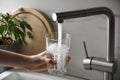 Woman filling glass with tap water from faucet in kitchen, closeup Royalty Free Stock Photo