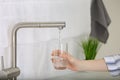 Woman filling glass with tap water from faucet in kitchen, closeup Royalty Free Stock Photo