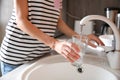 Woman filling glass with water from faucet in kitchen Royalty Free Stock Photo