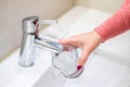 Woman filling glass with water from running water tap Royalty Free Stock Photo