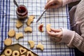 Woman filling homemade cookies with red currant jam