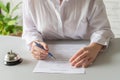 Woman filling hotel reservation form. Silver vintage bell on reception desk. Hotel service, registration. Royalty Free Stock Photo