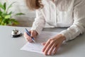 Woman filling hotel reservation form. Silver vintage bell on reception desk. Hotel service, registration. Royalty Free Stock Photo