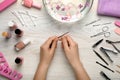 Woman filling nail at white wooden table, top view. Manicure procedure